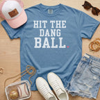Blue Jean Comfort Colors Hit The Dang Ball baseball game day shirt with white varsity lettering, styled as a casual baseball
mom outfit.