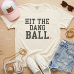 Ivory Comfort Colors baseball shirt featuring Hit The Dang Ball varsity design with pink heart, styled for a cute baseball mom outfit.