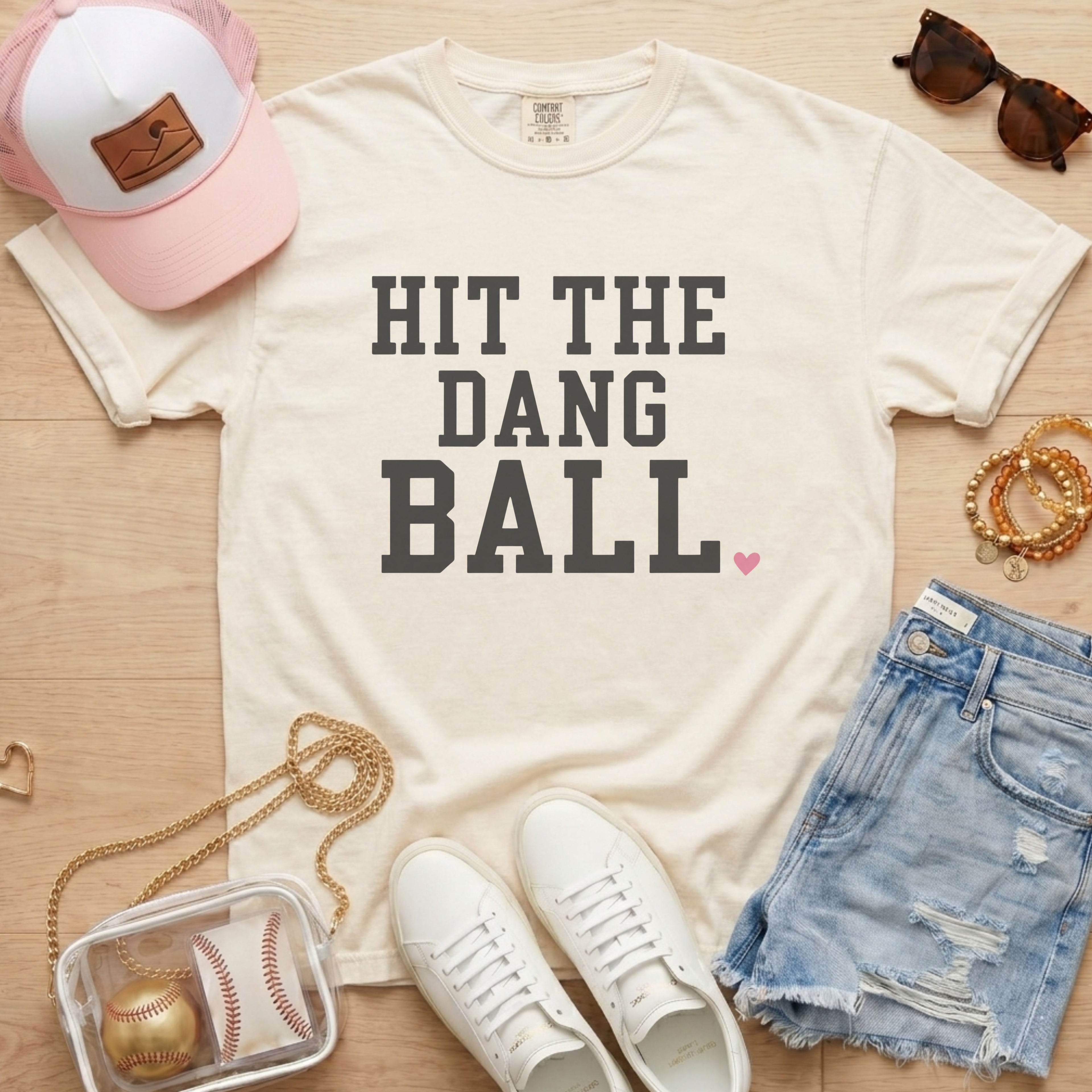Ivory Comfort Colors baseball shirt featuring Hit The Dang Ball varsity design with pink heart, styled for a cute baseball mom outfit.
