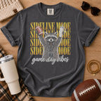 Charcoal gray football mom shirt, Comfort Colors Pepper, styled in a game day flat lay with a football and a raccoon holding a football and tumbler beneath “Sideline Mode” lettering.