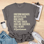 Gray t-shirt with '#Sportsmom' text on a wooden surface with accessories.