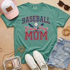 Green Comfort Colors baseball mom shirt with baseball bats graphic, sneakers, hat, and denim shorts