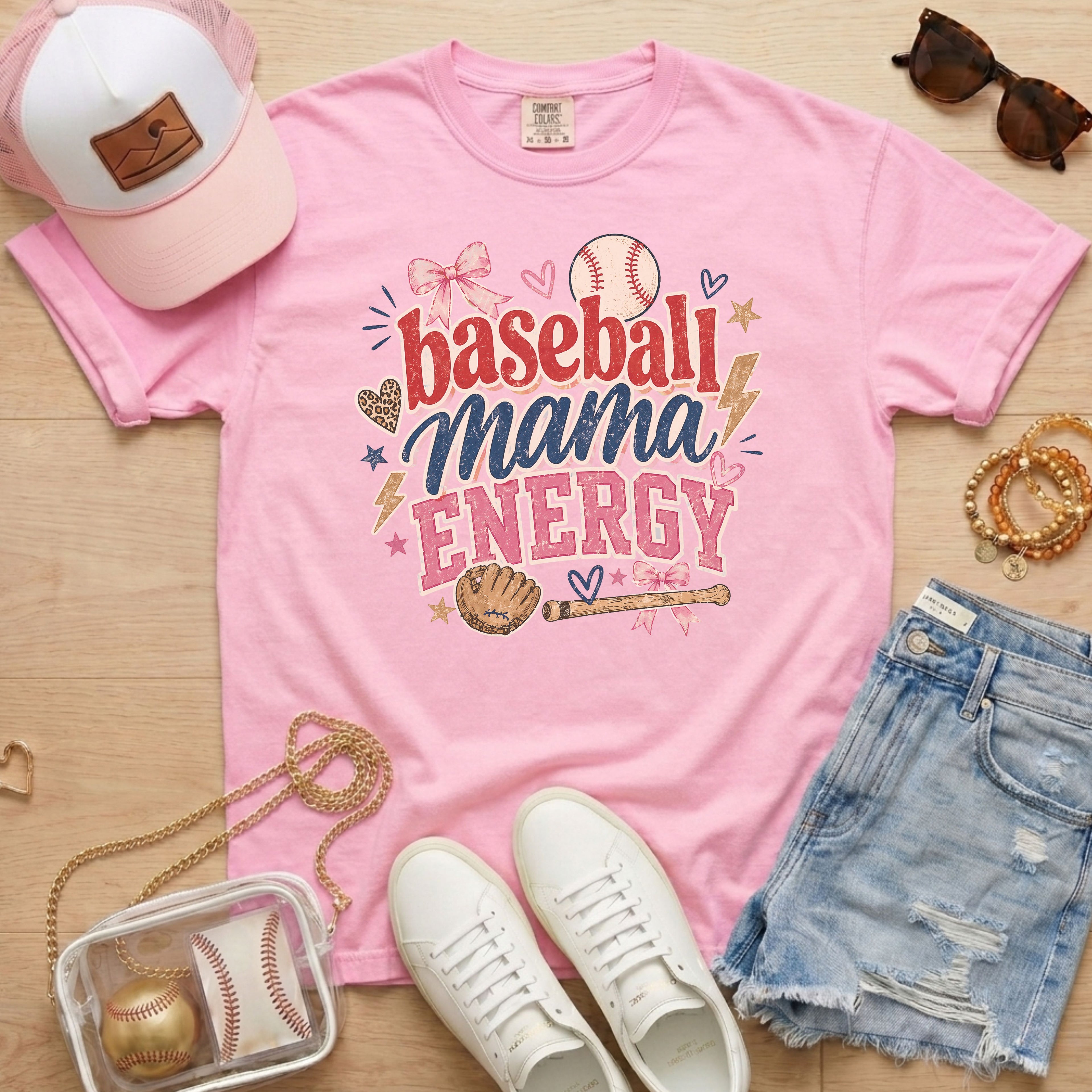 Baseball Mama Energy Comfort Colors blossom pink baseball mom shirt styled as flat lay with trucker hat, sunglasses, denim shorts, and sneakers