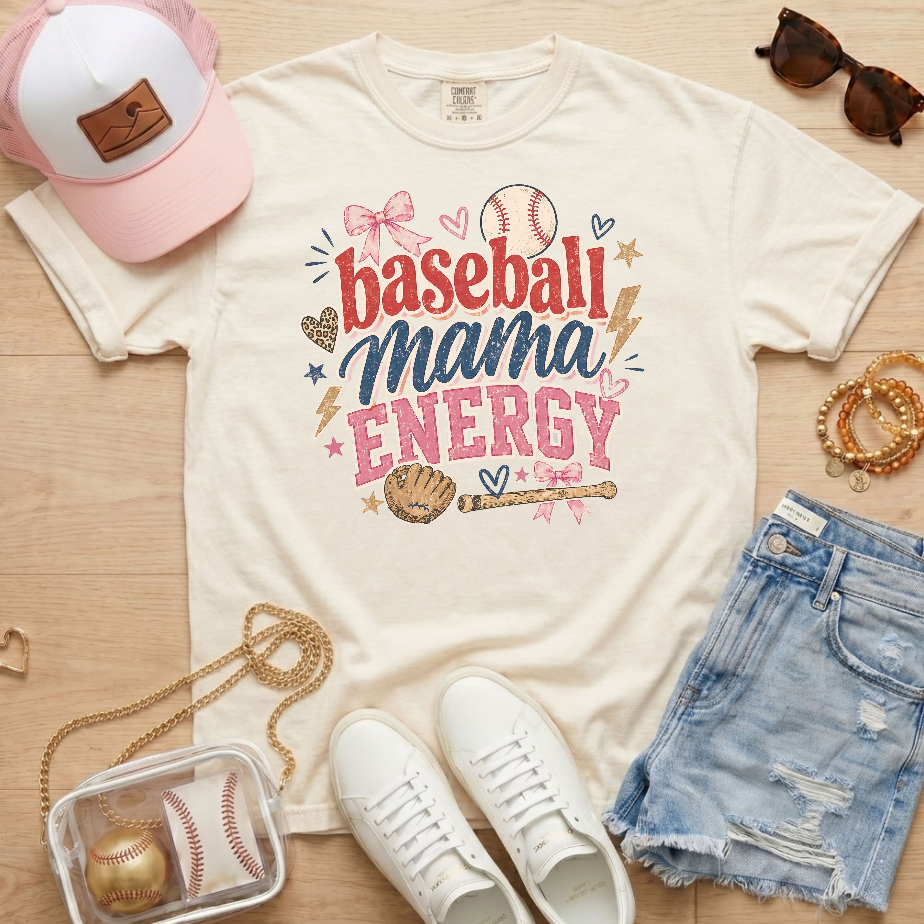 Baseball Mama Energy Comfort Colors blossom pink baseball mom shirt styled as flat lay with trucker hat, sunglasses, denim shorts, and sneakers