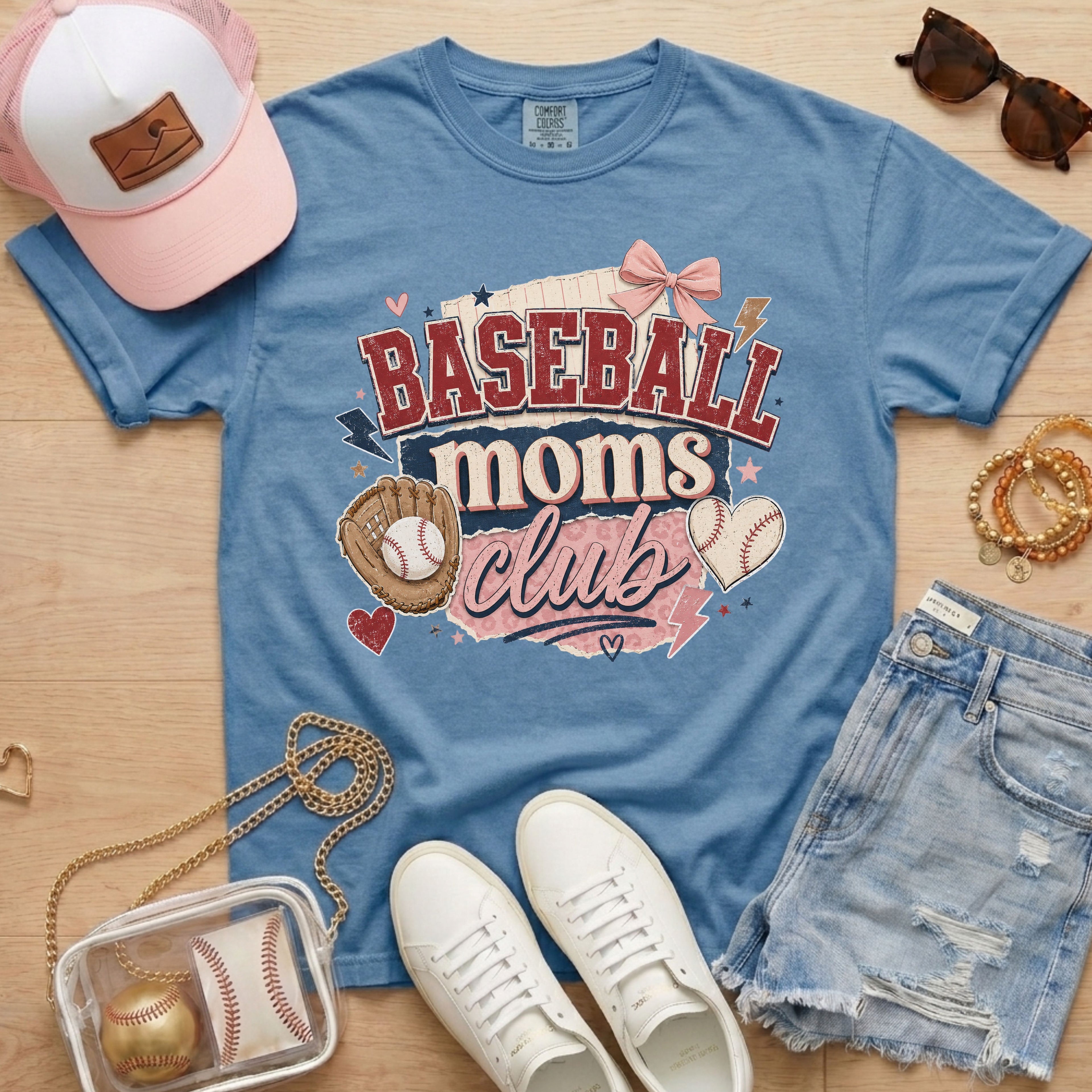 Baseball Moms Club Comfort Colors tee in blue jean flat lay with trucker hat, denim shorts, white sneakers, and baseball.