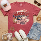 Baseball Moms Club Comfort Colors tee in crimson flat lay with trucker hat, denim shorts, white sneakers, and baseball.