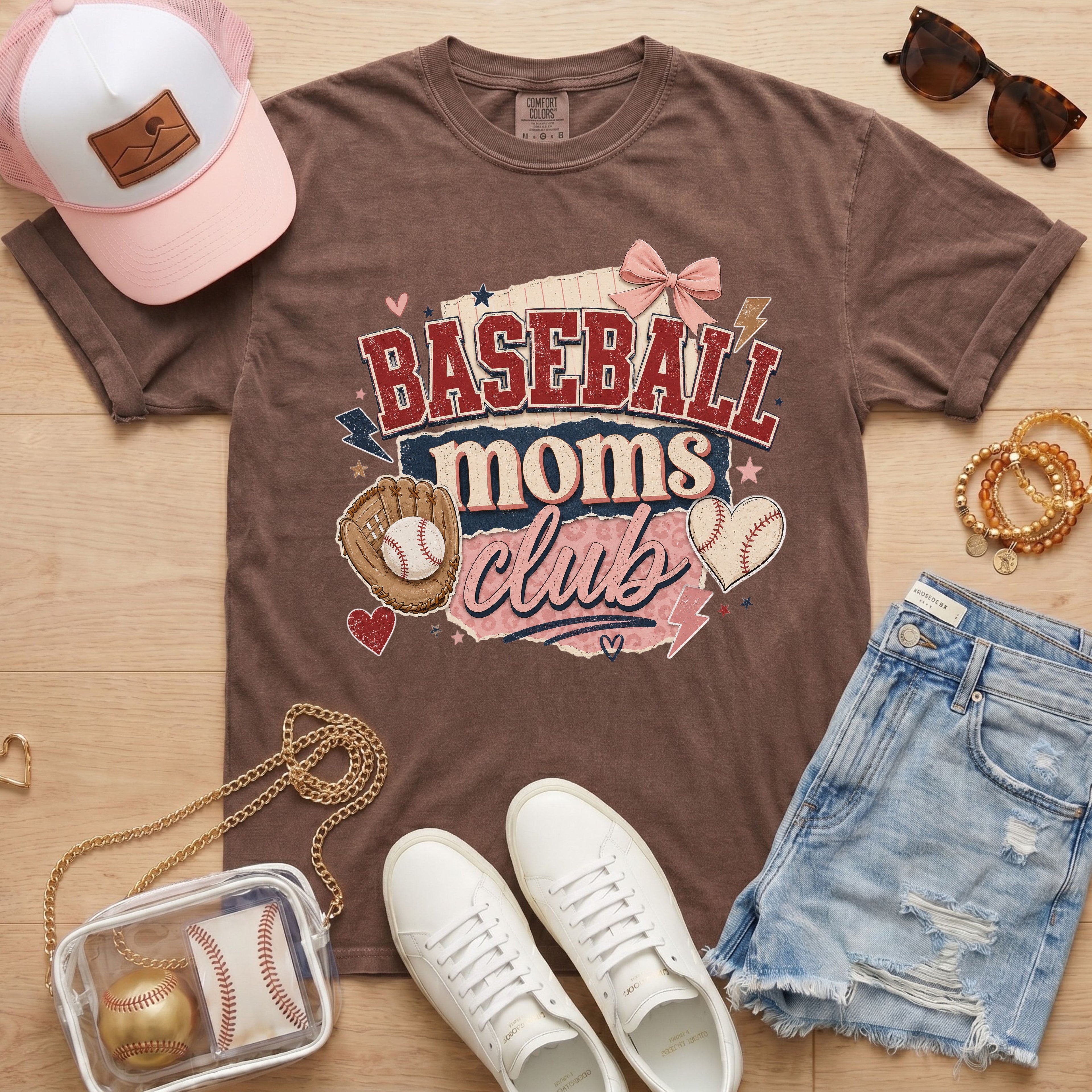 Baseball Moms Club Comfort Colors tee in espresso flat lay with trucker hat, denim shorts, white sneakers, and baseball.
