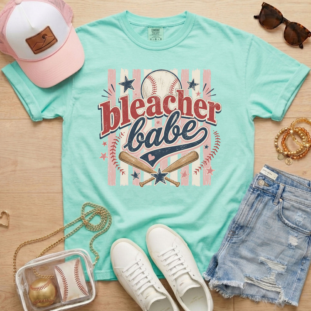 Bleacher Babe baseball mom Comfort Colors tee in chalky mint flat lay with trucker hat, denim shorts, white sneakers, and baseball.