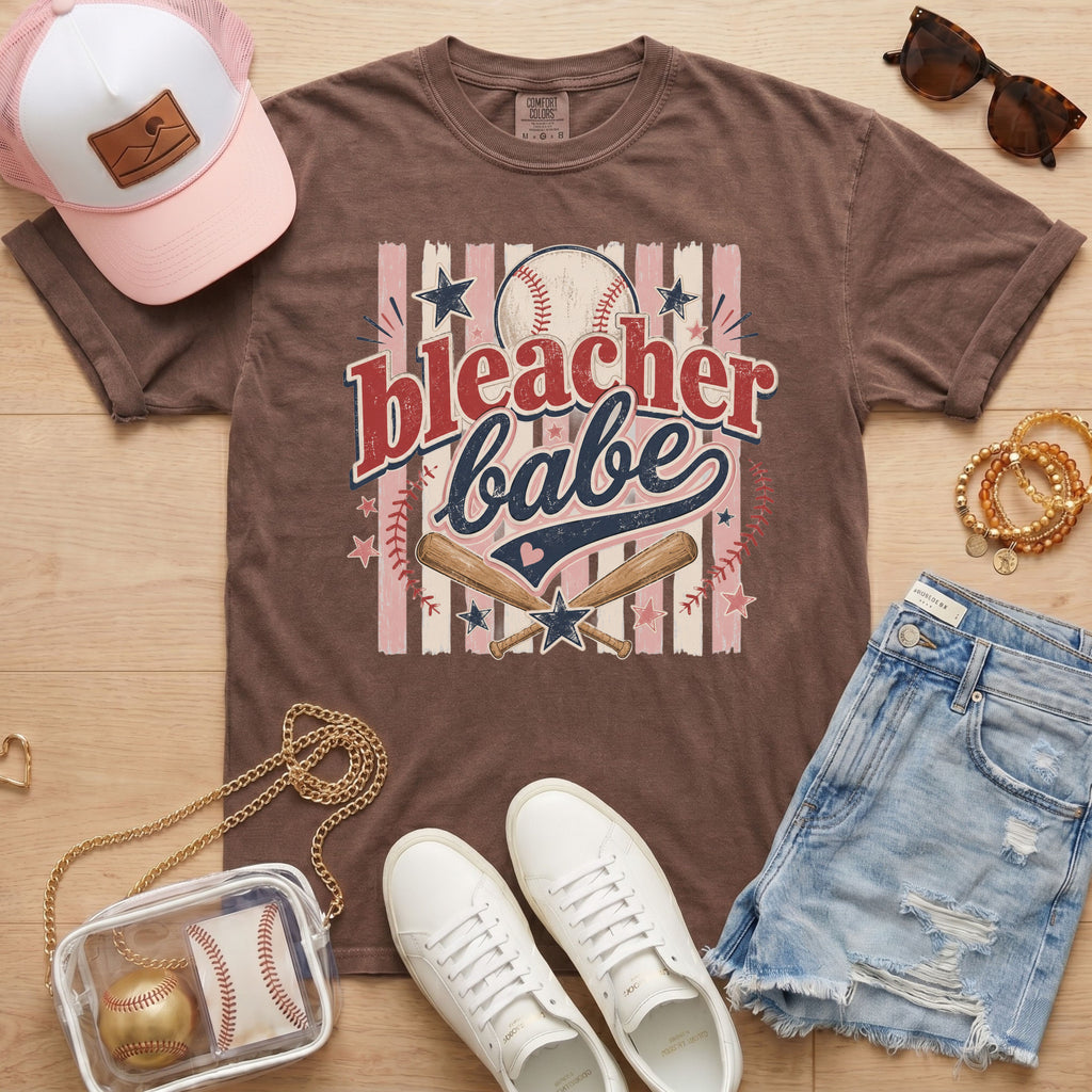 Bleacher Babe baseball mom Comfort Colors tee in espresso flat lay with trucker hat, denim shorts, white sneakers, and baseball