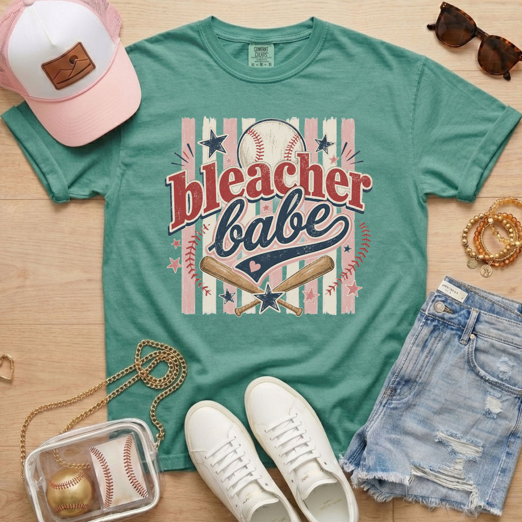 Bleacher Babe baseball mom Comfort Colors tee in light green flat lay with trucker hat, denim shorts, white sneakers, and baseball.