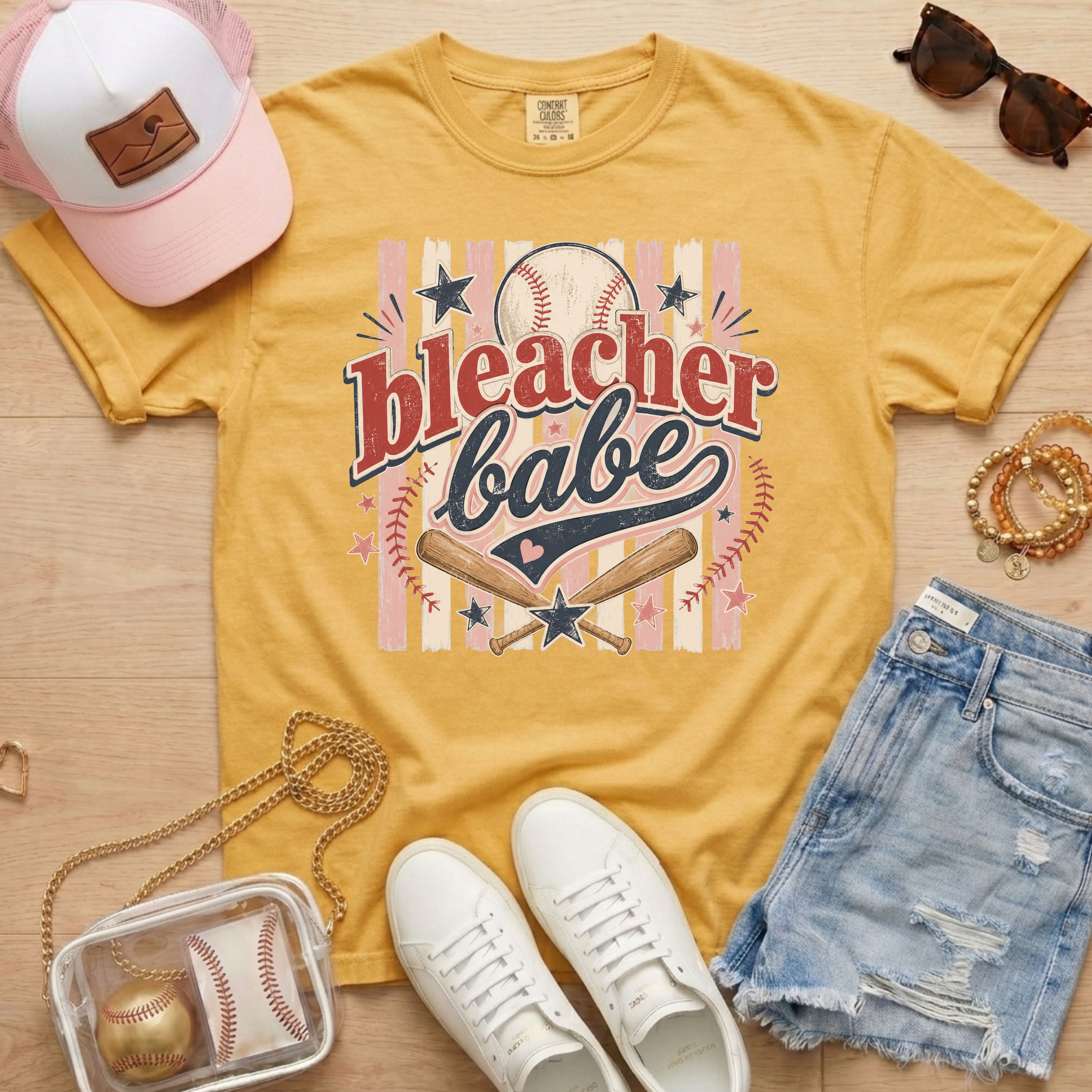 Bleacher Babe baseball mom Comfort Colors tee in mustard flat lay with trucker hat, denim shorts, white sneakers, and baseball.