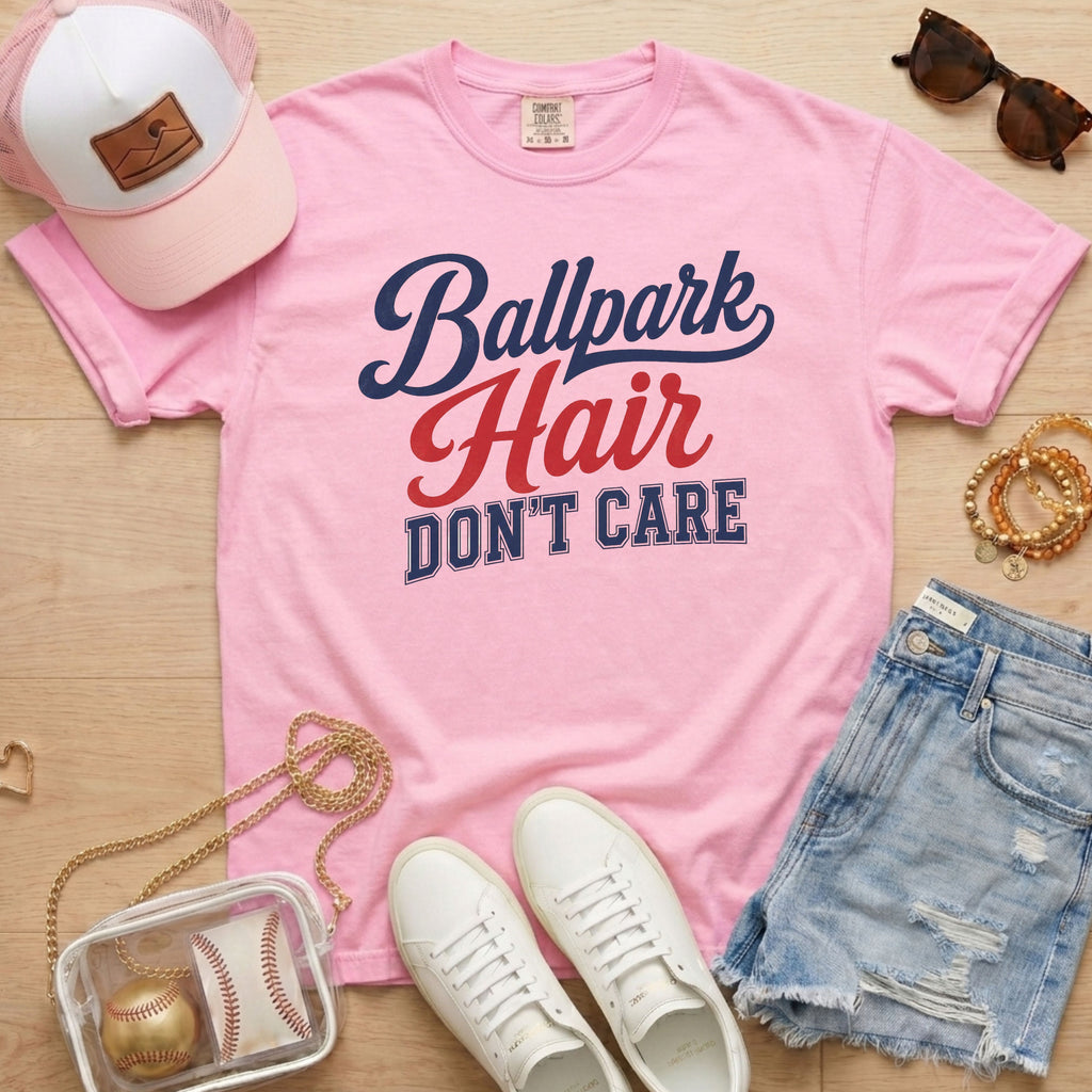 Blossom light pink Comfort Colors Ballpark Hair Don’t Care funny baseball mom shirt styled with denim shorts, sneakers, pink hat, sunglasses, and clear baseball bag.