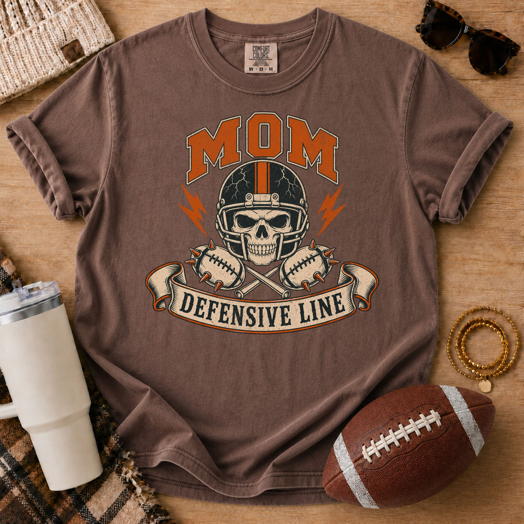Defensive line football mom graphic T-shirt in dark brown, Comfort Colors Espresso, styled in a football game day flat lay.