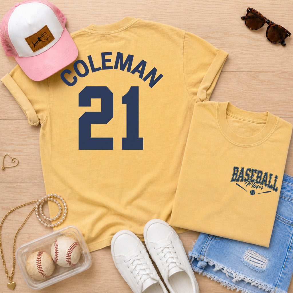 Yellow t-shirt with 'COLEMAN 21' design, pink and white cap, sunglasses, and baseballs on a wooden surface.