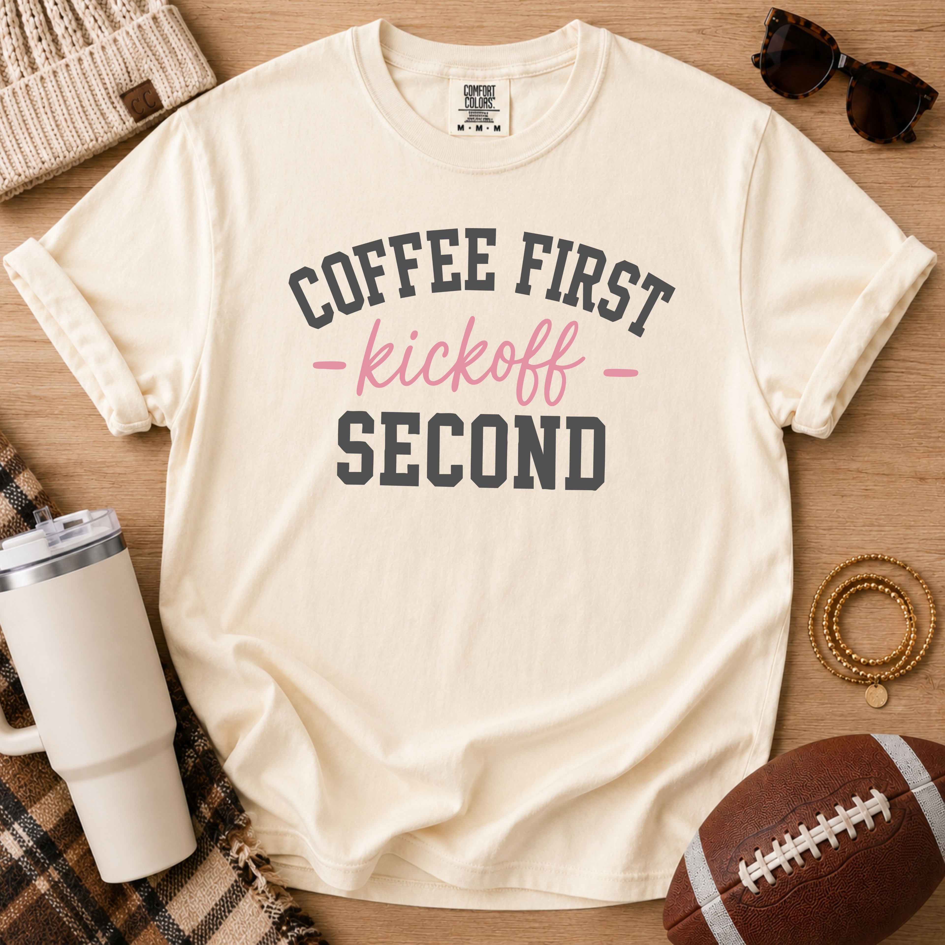 Ivory Comfort Colors football mom shirt with Coffee First Kickoff Second design and football prop.