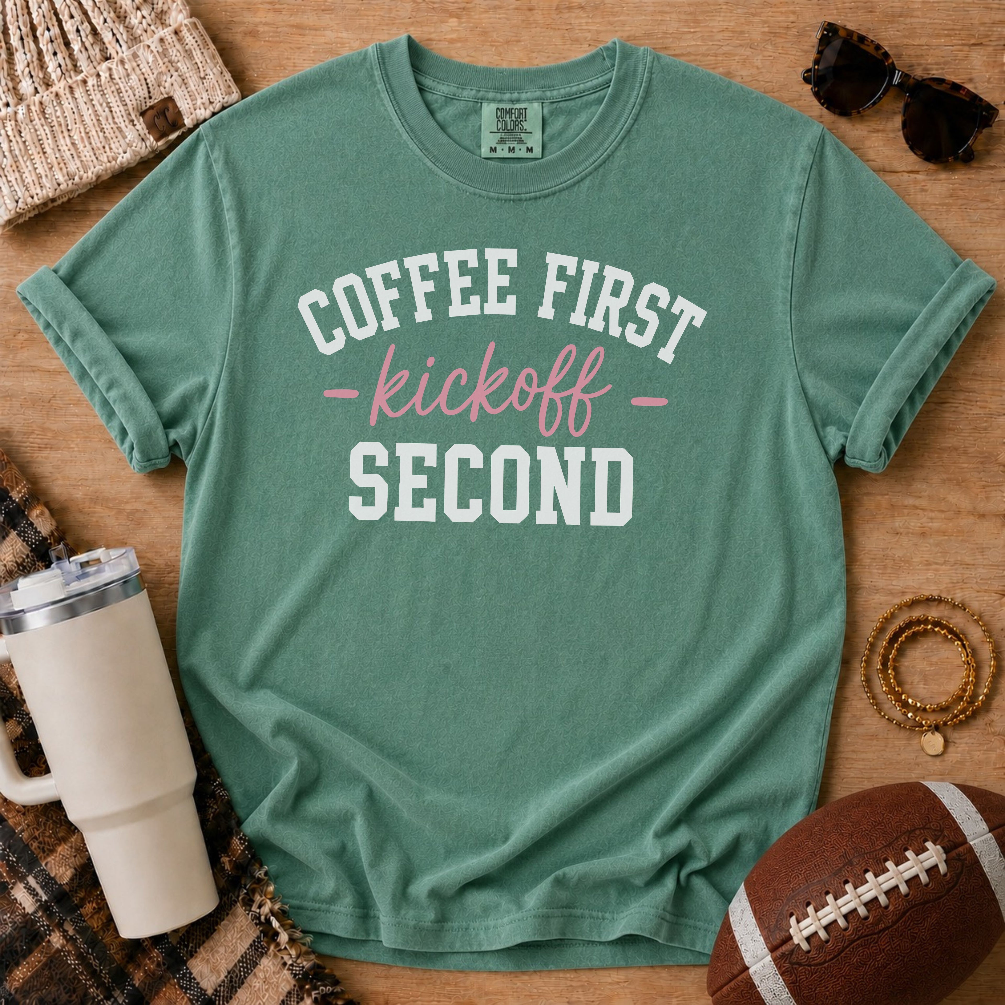 Light Green Comfort Colors football mom shirt with Coffee First Kickoff Second design and football prop.