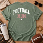 FOOTBALL MOM graphic shirt in olive green, Comfort Colors Moss, shown in a styled flat lay from the back.