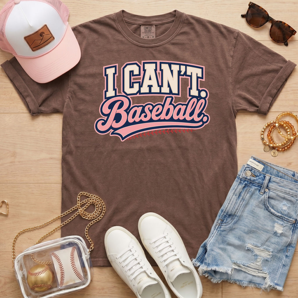 I CAN'T. Baseball. baseball mom Comfort Colors espresso tee in a boutique game day flat lay with hat, sneakers, denim shorts, and baseball bag.