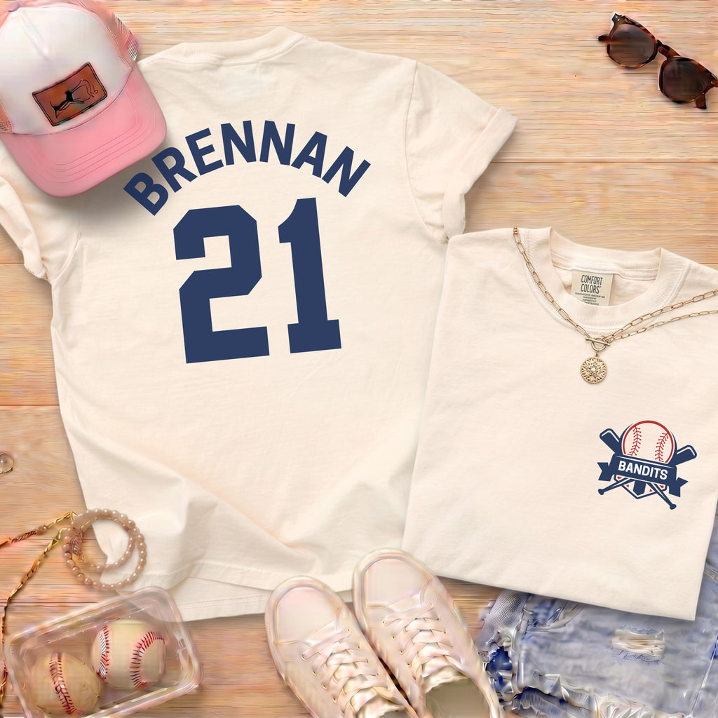 Ivory Comfort Colors shirt with navy blue Brennan 21 baseball player name and number on back and Bandits team logo