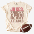 Running back mom graphic T-shirt in cream, Comfort Colors Ivory, shown with a football and the “Jukes, Snacks & Mini Heart Attacks” design.