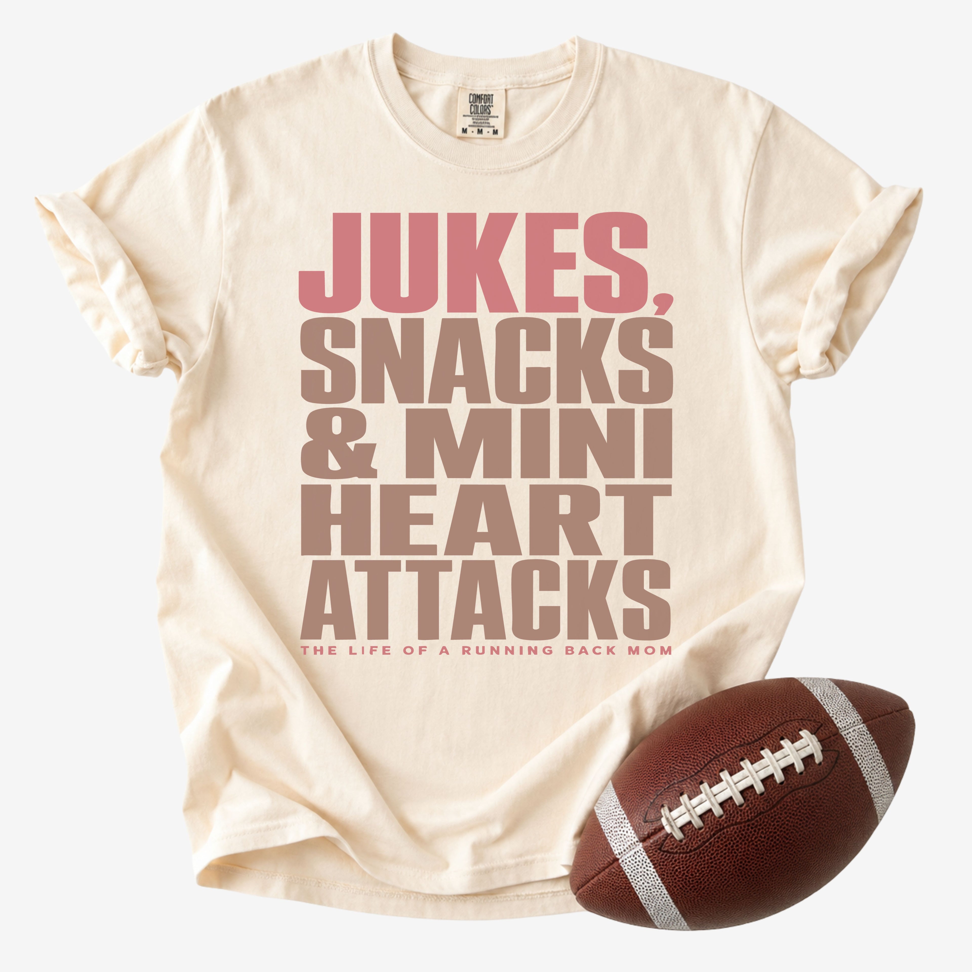 Running back mom graphic T-shirt in cream, Comfort Colors Ivory, shown with a football and the “Jukes, Snacks & Mini Heart Attacks” design.