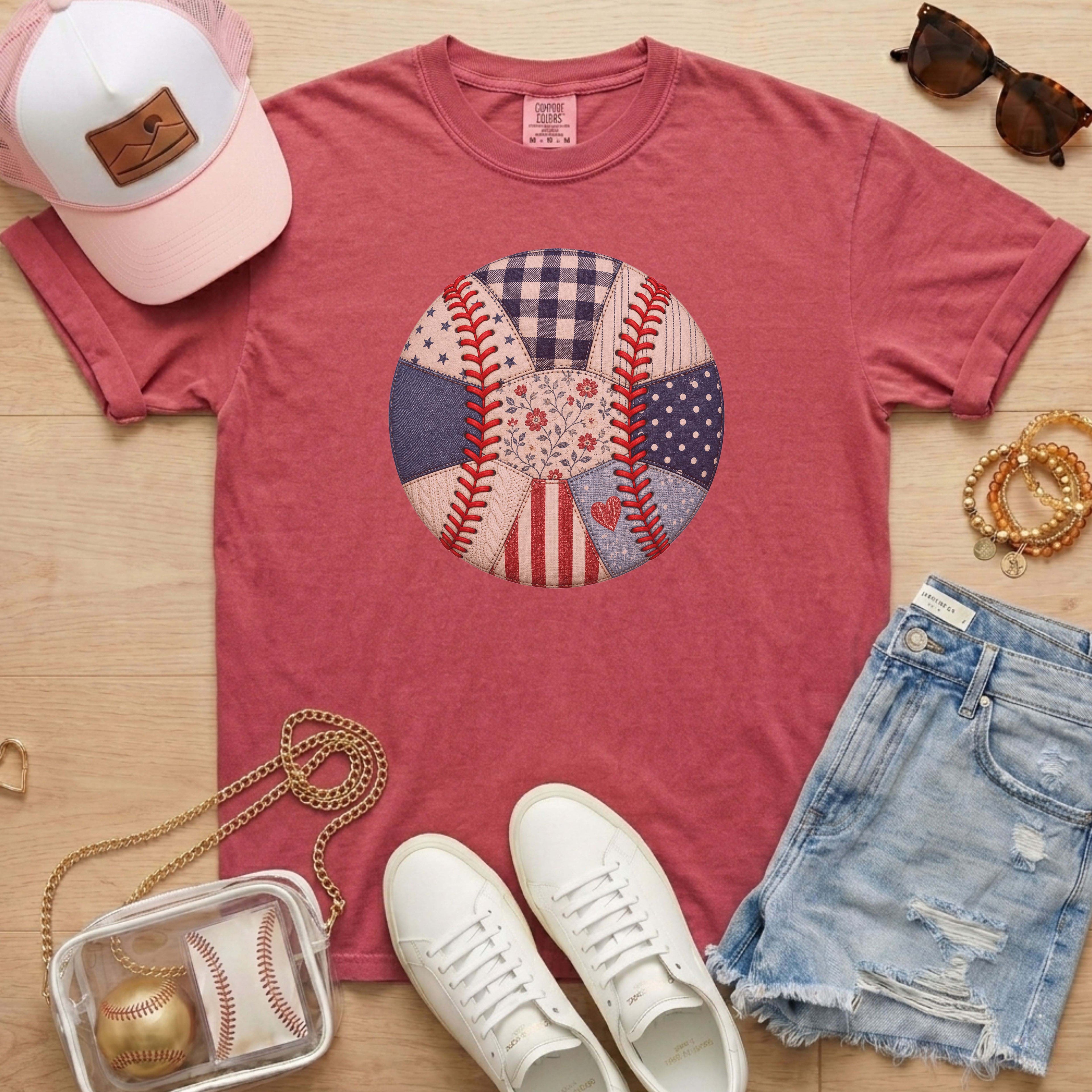 Red t-shirt with baseball design, white sneakers, denim shorts, pink cap, and small bag on a wooden surface.