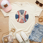 White t-shirt with a colorful patch design, white sneakers, denim shorts, pink cap, and sunglasses on a wooden surface.