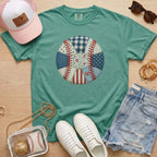 Green t-shirt with a baseball design, pink cap, white sneakers, denim shorts, and accessories on a wooden surface.