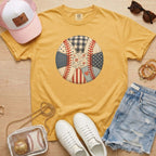 Yellow t-shirt with baseball design, white sneakers, pink cap, sunglasses, and denim shorts on a wooden surface.