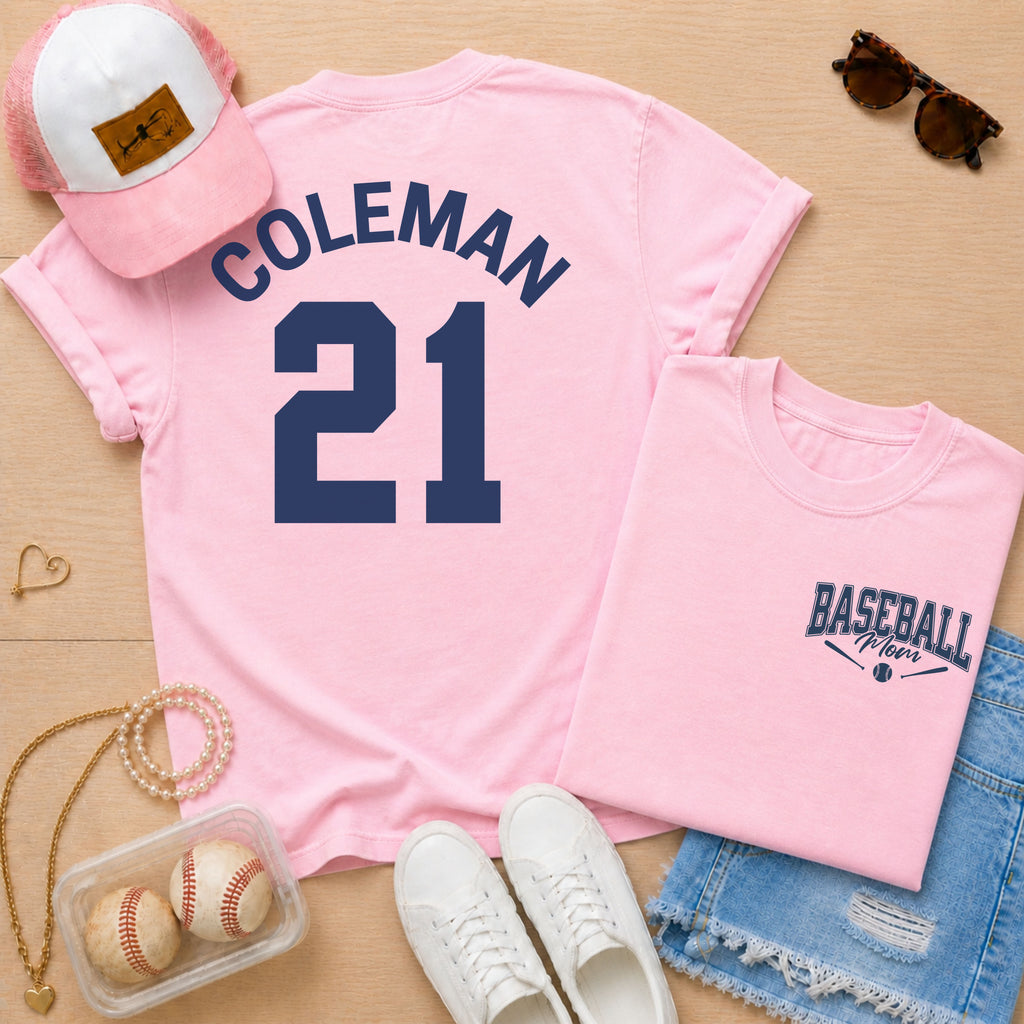 Pink t-shirt with 'COLEMAN 21' design, pink cap, sunglasses, and baseball-themed accessories on a wooden surface.