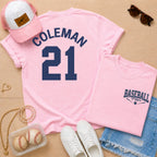 Pink t-shirt with 'COLEMAN 21' design, pink cap, sunglasses, and baseball-themed accessories on a wooden surface.