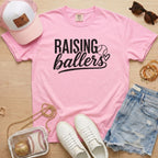 Raising Ballers baseball mom Comfort Colors blossom game day tee styled with hat, denim shorts, and baseball accessories