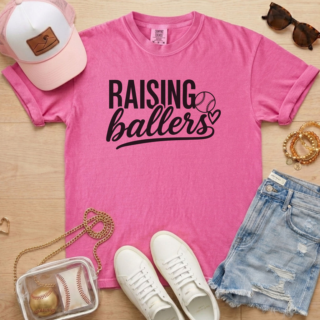 Raising Ballers baseball mom Comfort Colors crunchberry game day tee styled with hat, denim shorts, and baseball accessories