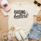 Raising Ballers baseball mom Comfort Colors ivory game day tee styled with hat, denim shorts, and baseball accessories