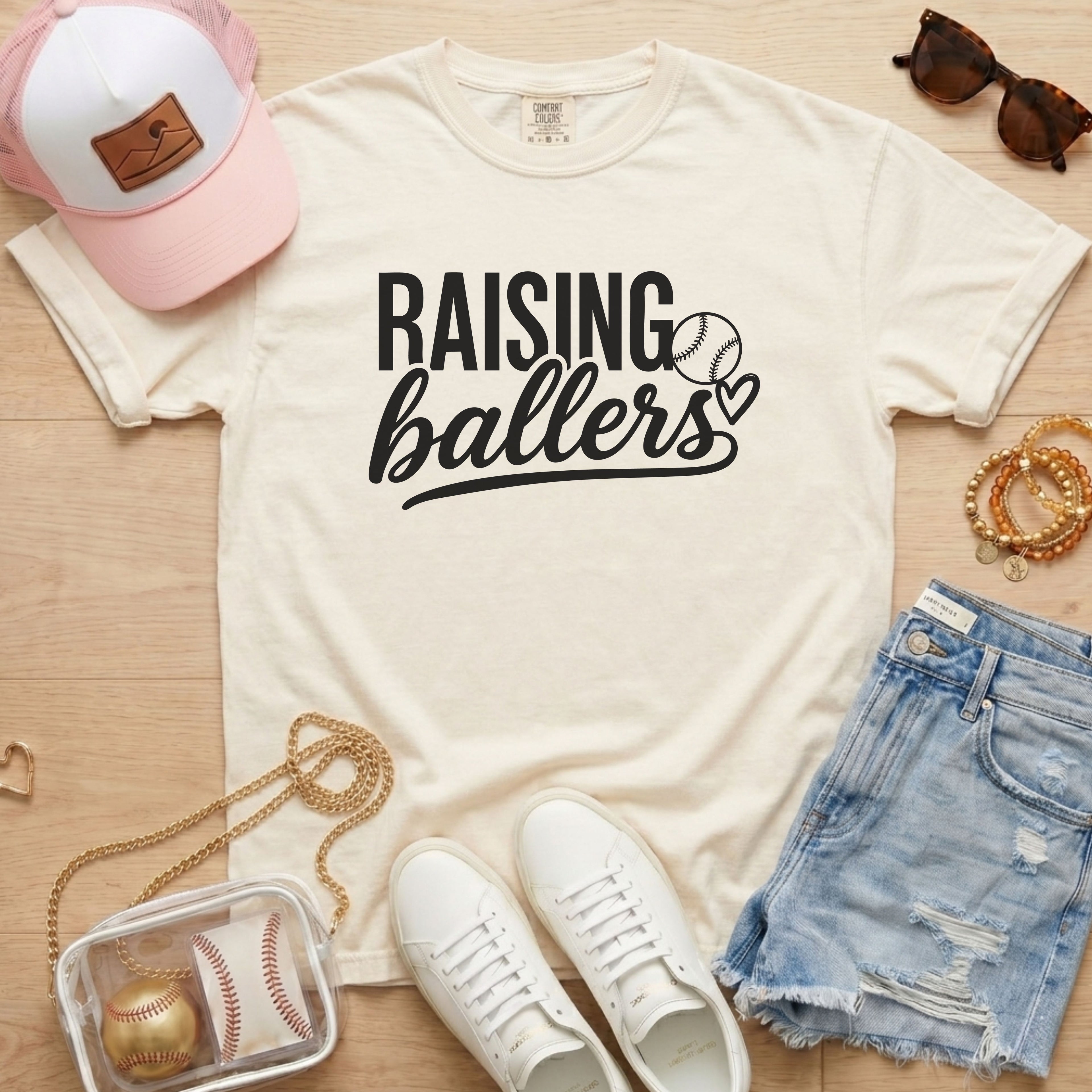 Raising Ballers baseball mom Comfort Colors ivory game day tee styled with hat, denim shorts, and baseball accessories