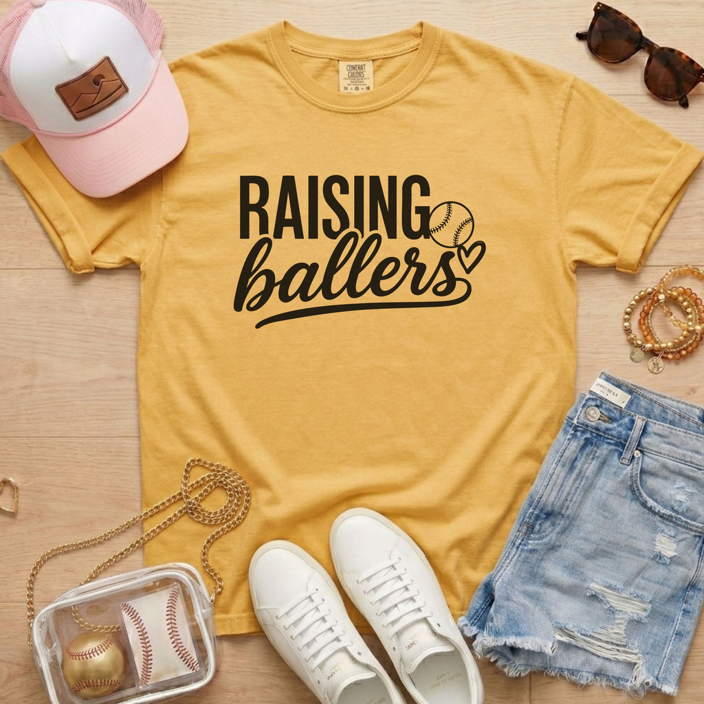 Raising Ballers baseball mom Comfort Colors mustard game day tee styled with hat, denim shorts, and baseball accessories