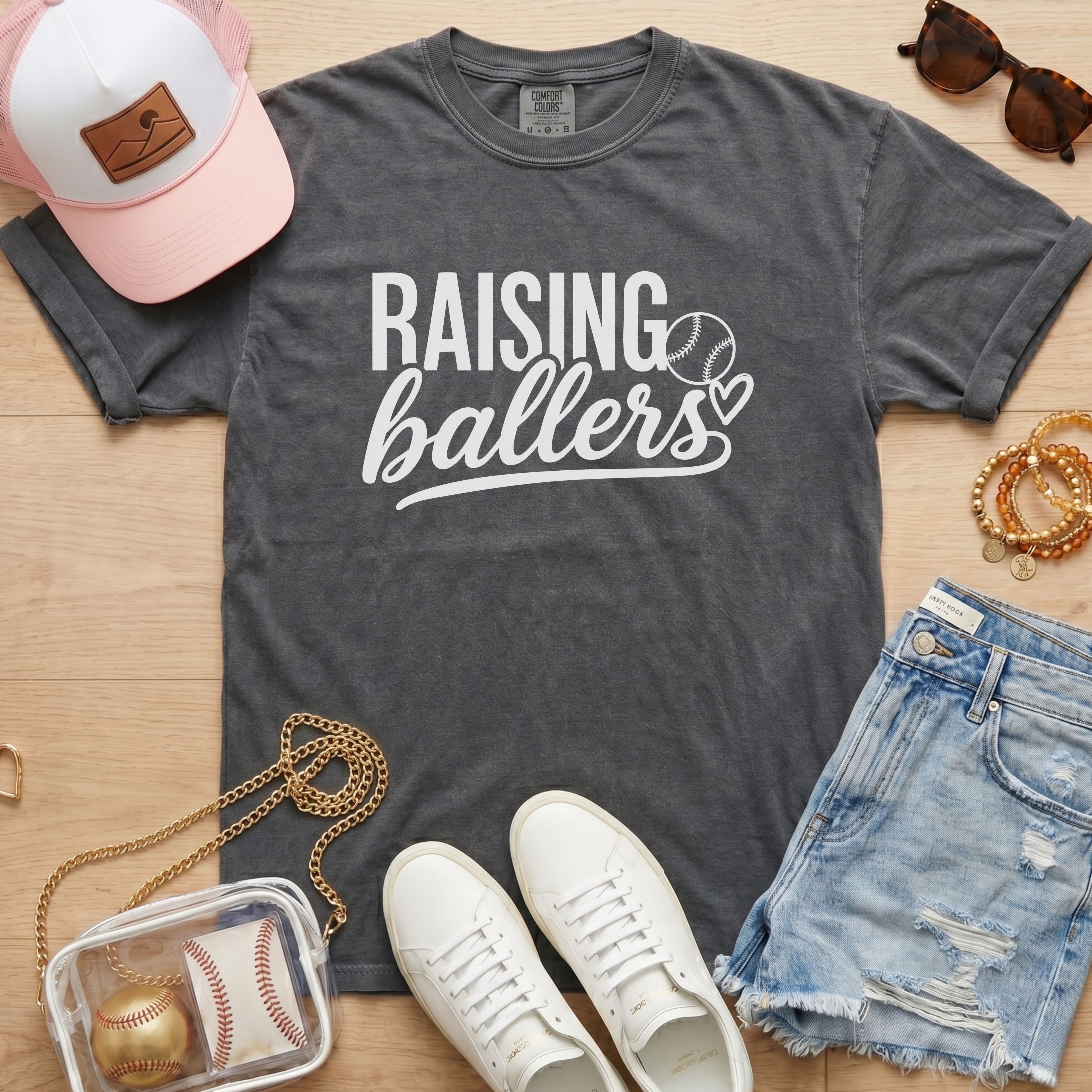Raising Ballers baseball mom Comfort Colors pepper game day tee styled with hat, denim shorts, and baseball accessories