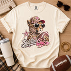 Cream football mom graphic T-shirt, Comfort Colors Ivory, featuring a leopard in jeweled sunglasses and cap holding a football above “Sideline Chic” lettering.