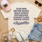 Team Mom Uniform Washer Snack Bringer baseball mom Comfort Colors Ivory tee flat lay with pink trucker hat, baseball purse, white sneakers, denim shorts, sunglasses, and jewelry.