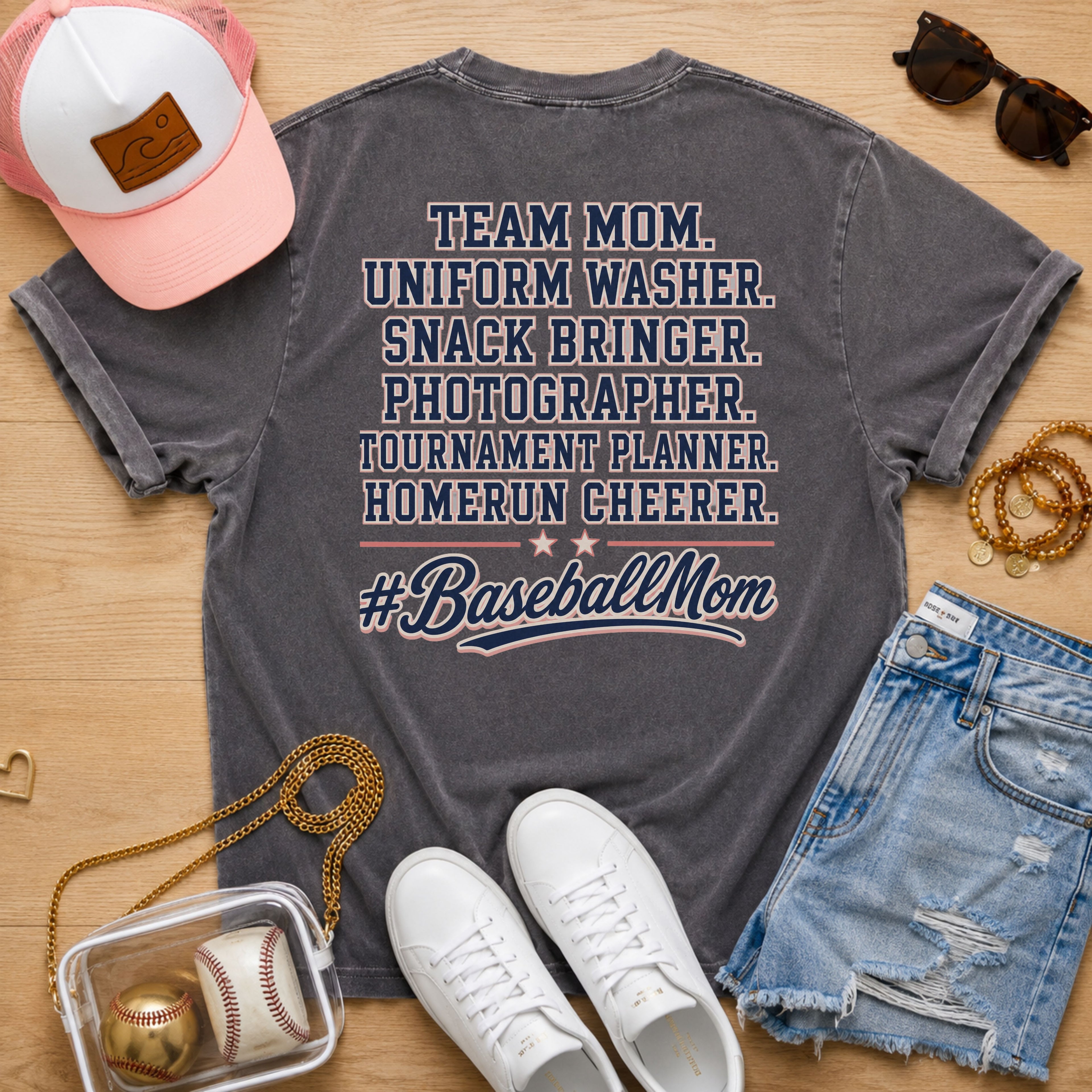 Team Mom Uniform Washer Snack Bringer baseball mom Comfort Colors Pepper tee flat lay with pink trucker hat, baseball purse, white sneakers, denim shorts, sunglasses, and jewelry.