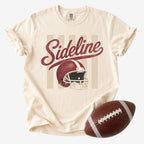 Vintage football graphic T-shirt in cream, Comfort Colors Ivory, featuring distressed red “Sideline” script and a retro football helmet.